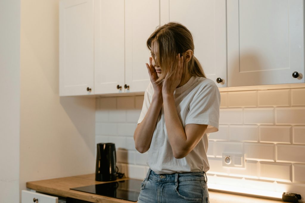 A woman in a modern kitchen looking distressed, emphasizing mental health awareness.